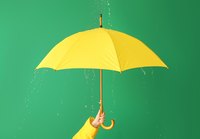 Eine Hand hält einen großen gelben Regenschirm, während Wasser von oben herab auf ihn tropft. Der Hintergrund ist grün, was den Kontrast zum Regenschirm verstärkt. Die Szene vermittelt eine fröhliche Stimmung trotz des Regens.
