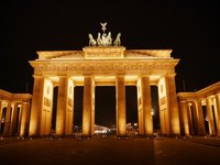 Das Bild zeigt das Brandenburger Tor in Berlin bei Nacht, elegant beleuchtet. Die majestätischen Säulen und die Quadriga auf dem Tor stehen im Mittelpunkt und symbolisieren historische Bedeutung und Weltoffenheit. Der dunkle Himmel hebt die warmen Lichttöne hervor.