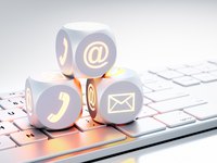 Weiße Würfel mit leuchtenden Kommunikations-Symbolen auf weißer Tastatur