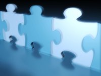 Drei Puzzlestücke in verschiedenen Blautönen stehen nebeneinander. Die etwas transparenten Teile sind an den Kanten glatt und zeigen die charakteristische Form von Puzzlestücken. Der Hintergrund ist dunkel, was die Puzzlestücke hervorhebt.