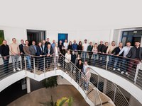 Das Team der gasuf steht auf einer geschwungenen Treppe in einem modernen Bürogebäude. Die Menschen sind in formeller und legerer Kleidung gekleidet, lächeln und posieren für das Foto. Im Hintergrund sind helle Wände und einige Kunstwerke sichtbar.